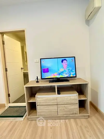 Modern living room with wooden TV stand and flat-screen television, showcasing minimalist design.