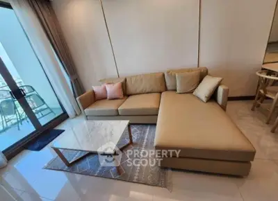 Modern living room with stylish beige sofa and marble coffee table, adjacent to a balcony with a view.