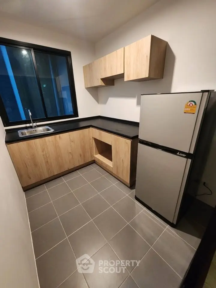 Modern kitchen with sleek cabinetry and stainless steel fridge in a compact layout.