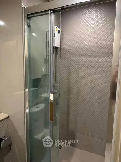 Modern bathroom with sleek glass shower enclosure and textured wall tiles.