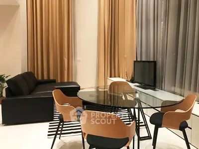 Modern living room with glass dining table, stylish chairs, and cozy sofa, featuring elegant floor-to-ceiling curtains.