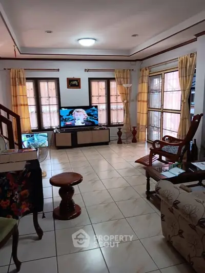 Spacious living room with tiled flooring and large windows for natural light.