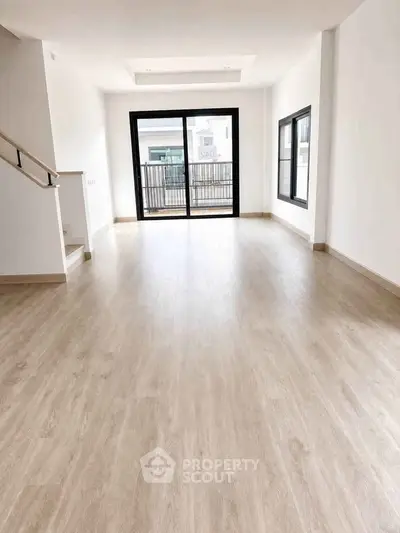 Spacious modern living room with large windows and wooden flooring, perfect for natural light and open living.