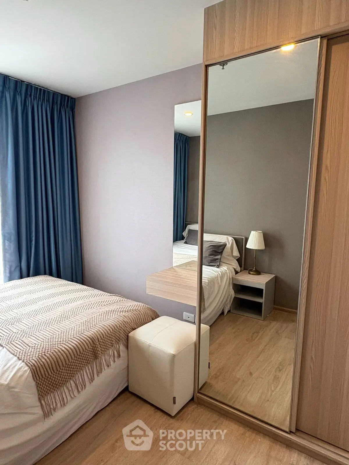 Cozy bedroom with modern decor, featuring a large mirror and stylish furnishings.