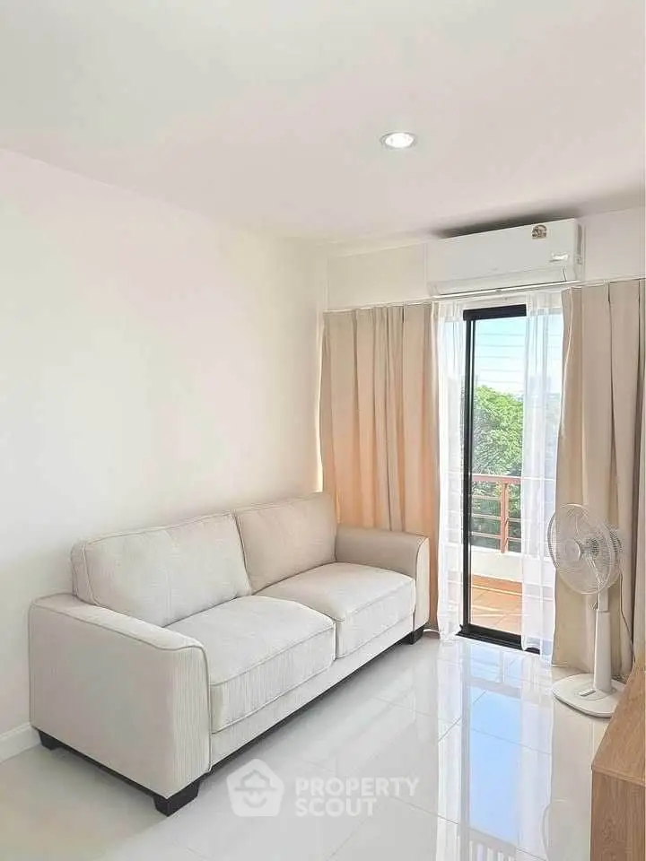 Bright living room with white sofa, air conditioning, and balcony view