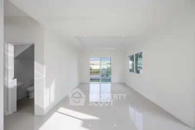 Spacious modern living room with large windows and glossy tiled floor, offering abundant natural light.