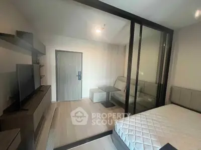 Modern studio apartment with glass partition, cozy living area, and sleek furnishings.