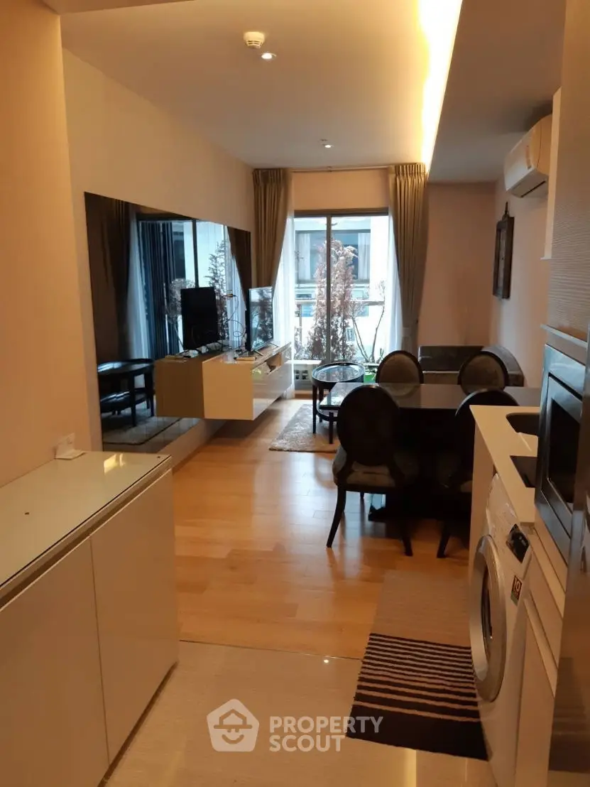 Modern living room with dining area and washing machine, featuring elegant decor and natural light.