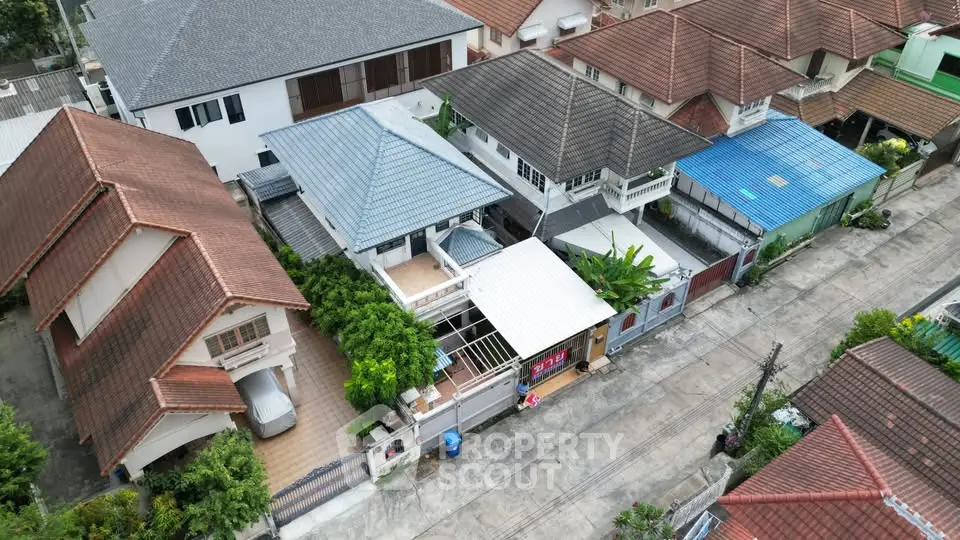 Aerial view of suburban homes with diverse roof styles and lush greenery in a peaceful neighborhood.