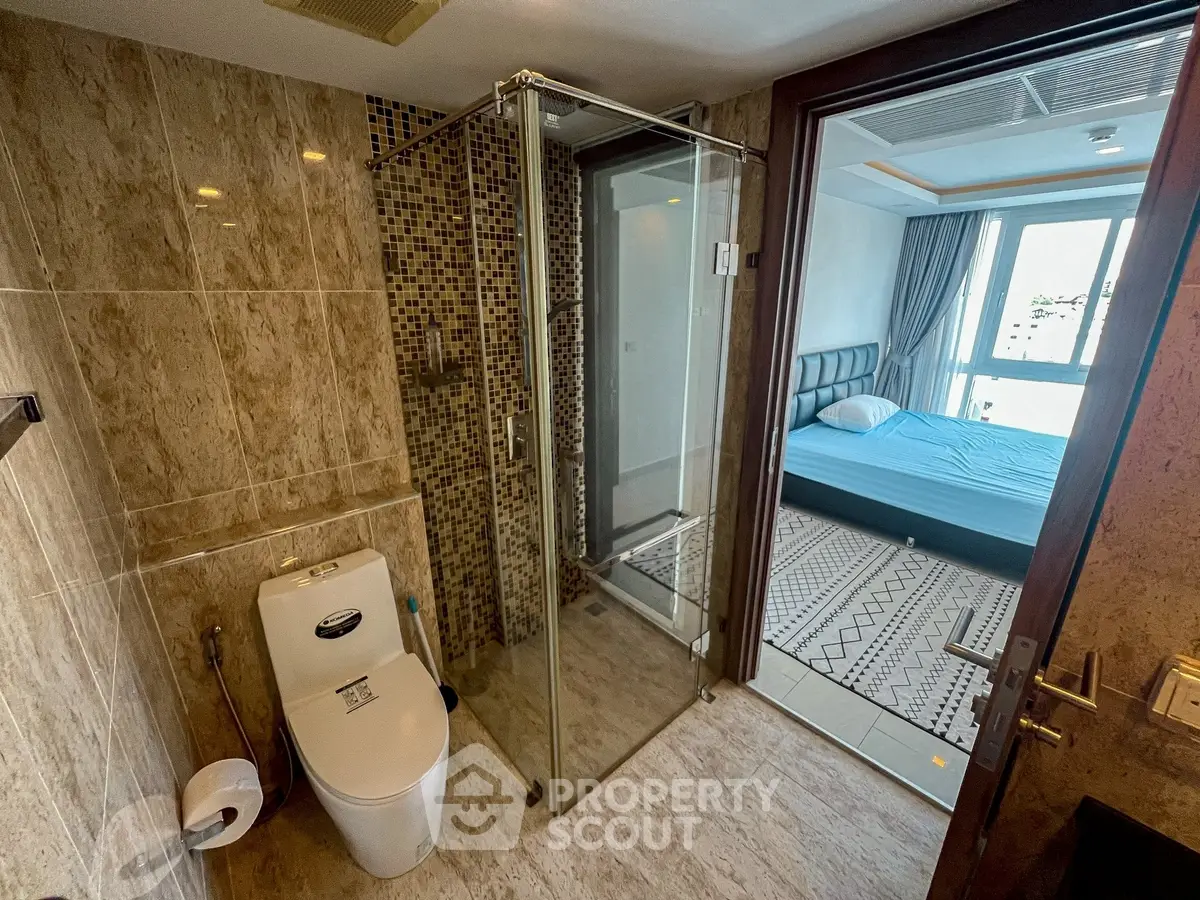 Modern bathroom with glass shower and view into stylish bedroom