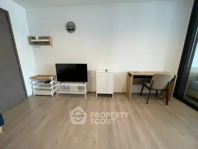 Modern minimalist living room with TV, desk, and wooden flooring.