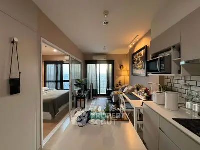 Modern open-plan apartment with kitchen and living area, featuring sleek design and natural light.