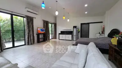 Spacious open-plan living room with modern decor and large windows overlooking greenery.