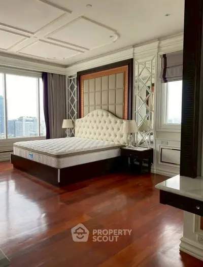 Luxurious bedroom with elegant decor and city view, featuring hardwood floors and plush headboard.