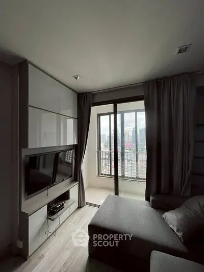 Modern living room with large window and city view, featuring sleek furniture and neutral tones.