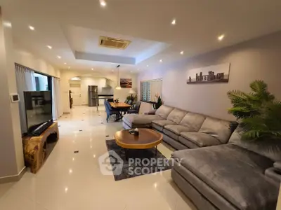 Spacious modern living room with open kitchen, elegant decor, and ample natural light.