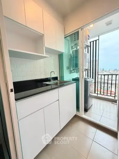 Modern kitchen with sleek cabinetry and balcony view in urban apartment