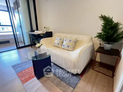 Modern living room with cozy sofa and glass table, open to a bright balcony view.