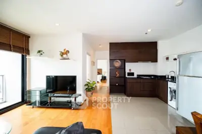 Modern open-plan living room with kitchen, featuring hardwood floors and sleek appliances.