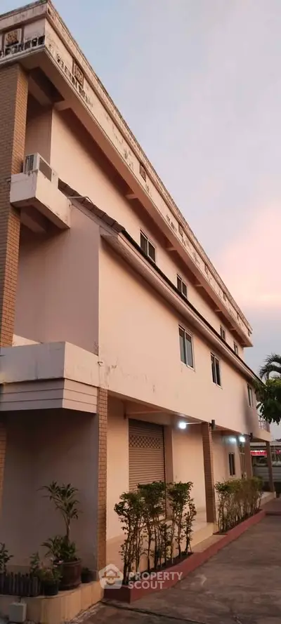 Charming multi-story building with modern facade and lush landscaping at sunset.