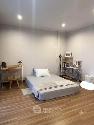 Minimalist bedroom with floor mattress and wooden flooring, perfect for cozy living.