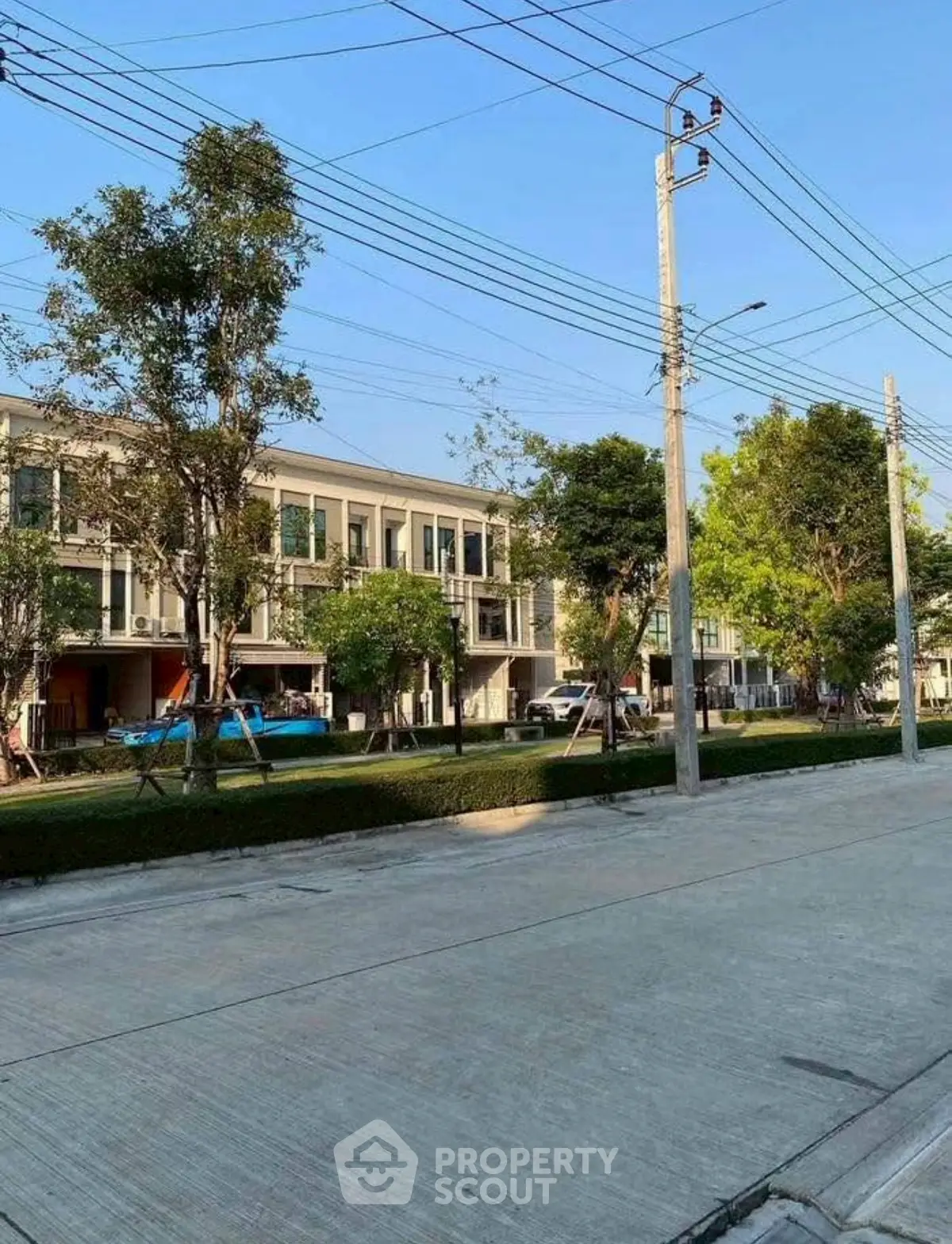 Modern townhouse exterior with lush greenery and clear blue sky.