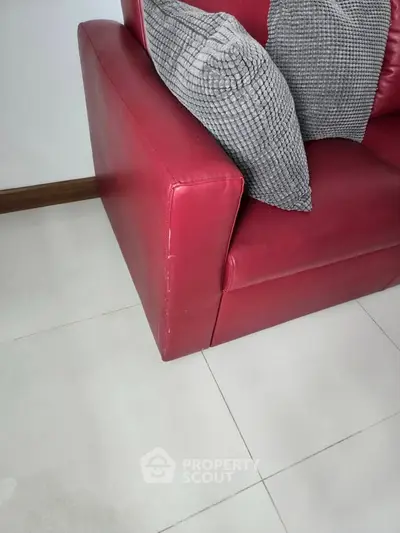 Modern red leather sofa with textured gray cushions on sleek tiled floor, perfect for stylish living room.