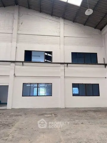 Spacious industrial warehouse interior with high ceilings and large windows.