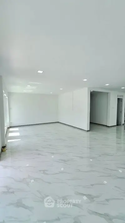 Spacious modern living room with elegant marble flooring and ample natural light.