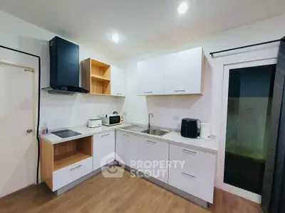 Modern kitchen with sleek white cabinets and wooden flooring, featuring built-in appliances and ample counter space.