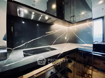 Luxurious modern kitchen with sleek black marble countertops and built-in oven, featuring elegant lighting.