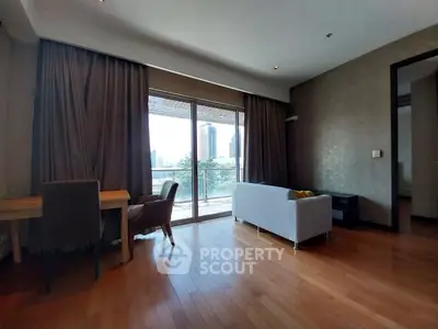Spacious living room with balcony and city view, featuring elegant wooden flooring and modern furniture.