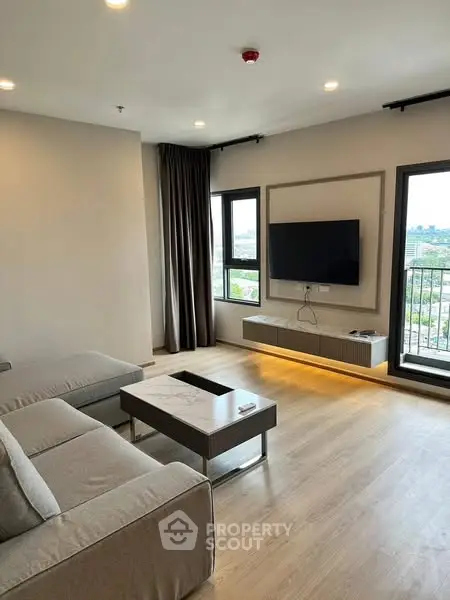 Modern living room with sleek furniture and large windows offering city views.