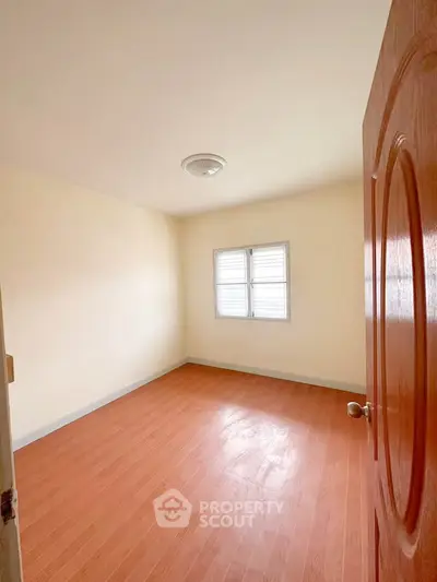 Spacious empty bedroom with wooden flooring and natural light