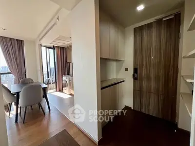 Modern apartment interior with dining area and entrance, featuring sleek design and natural light.