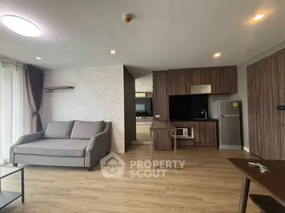 Modern living room with stylish furniture and open kitchen layout, featuring a cozy sofa and sleek appliances.