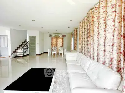 Spacious living room with elegant white sofa and floral curtains, perfect for modern family living.
