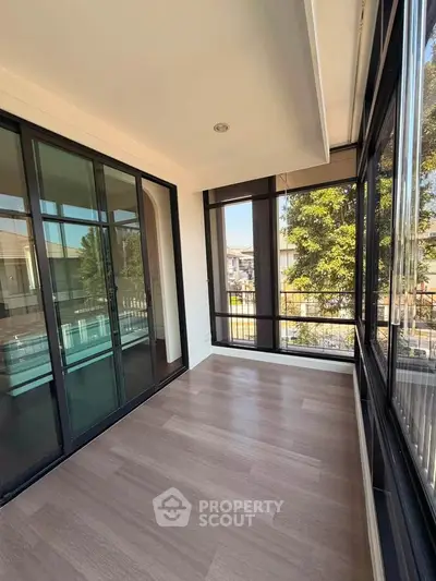 Spacious sunlit balcony with large glass doors and scenic view, perfect for relaxation and enjoying the outdoors.