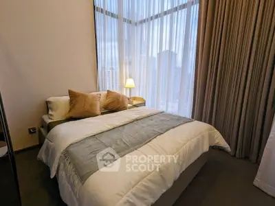 Luxurious bedroom with floor-to-ceiling windows and city view, featuring elegant decor and plush bedding.