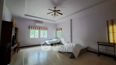 Spacious bedroom with twin beds and ceiling fan in a serene setting