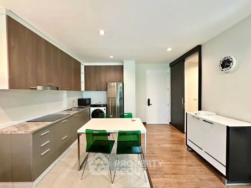 Modern kitchen with sleek cabinetry, dining area, and stainless steel appliances in a contemporary apartment.