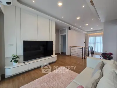 Spacious modern living room with sleek design and large TV, perfect for relaxation and entertainment.