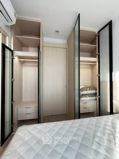 Modern bedroom with built-in wardrobes and sleek glass doors, showcasing ample storage space.