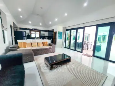 Spacious modern living room with elegant furniture and large glass doors leading to a bright outdoor area.