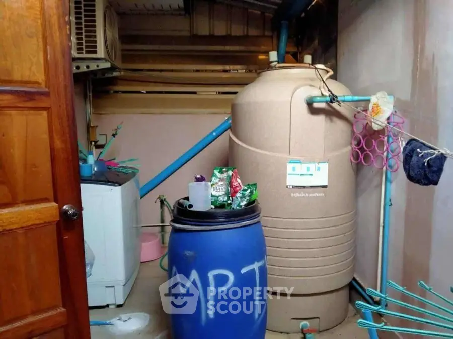 Utility room with water tank and washing machine, ideal for efficient home management.