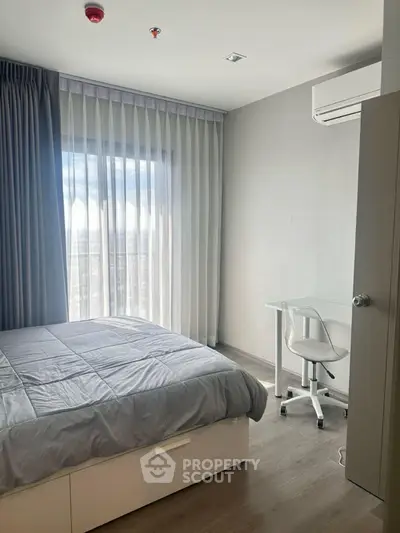 Modern bedroom with large window and study area in a stylish apartment.