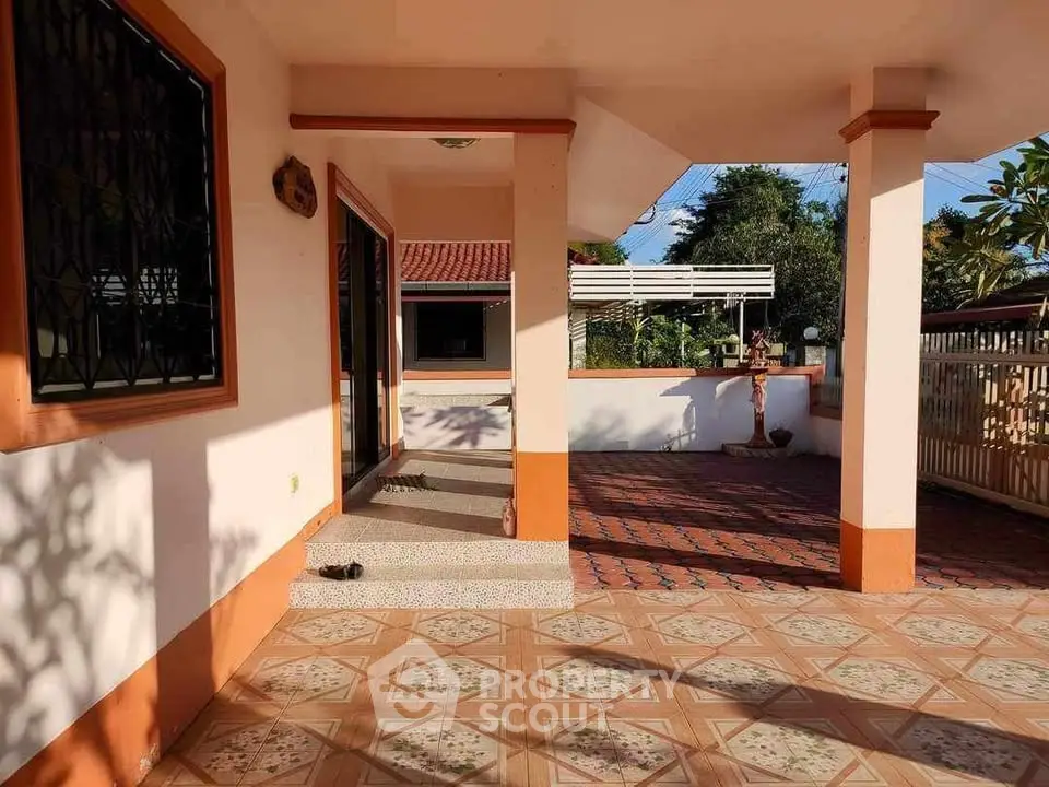 Charming outdoor patio with tiled flooring and garden view, perfect for relaxation.