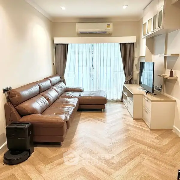 Modern living room with leather sofa and entertainment unit, featuring sleek design and natural light.
