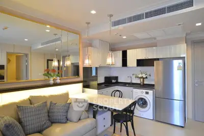 Modern open-layout kitchen with cozy living area, featuring sleek appliances and stylish lighting.