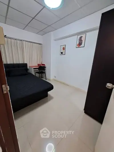 Cozy bedroom with modern decor and sleek black furniture, perfect for urban living.